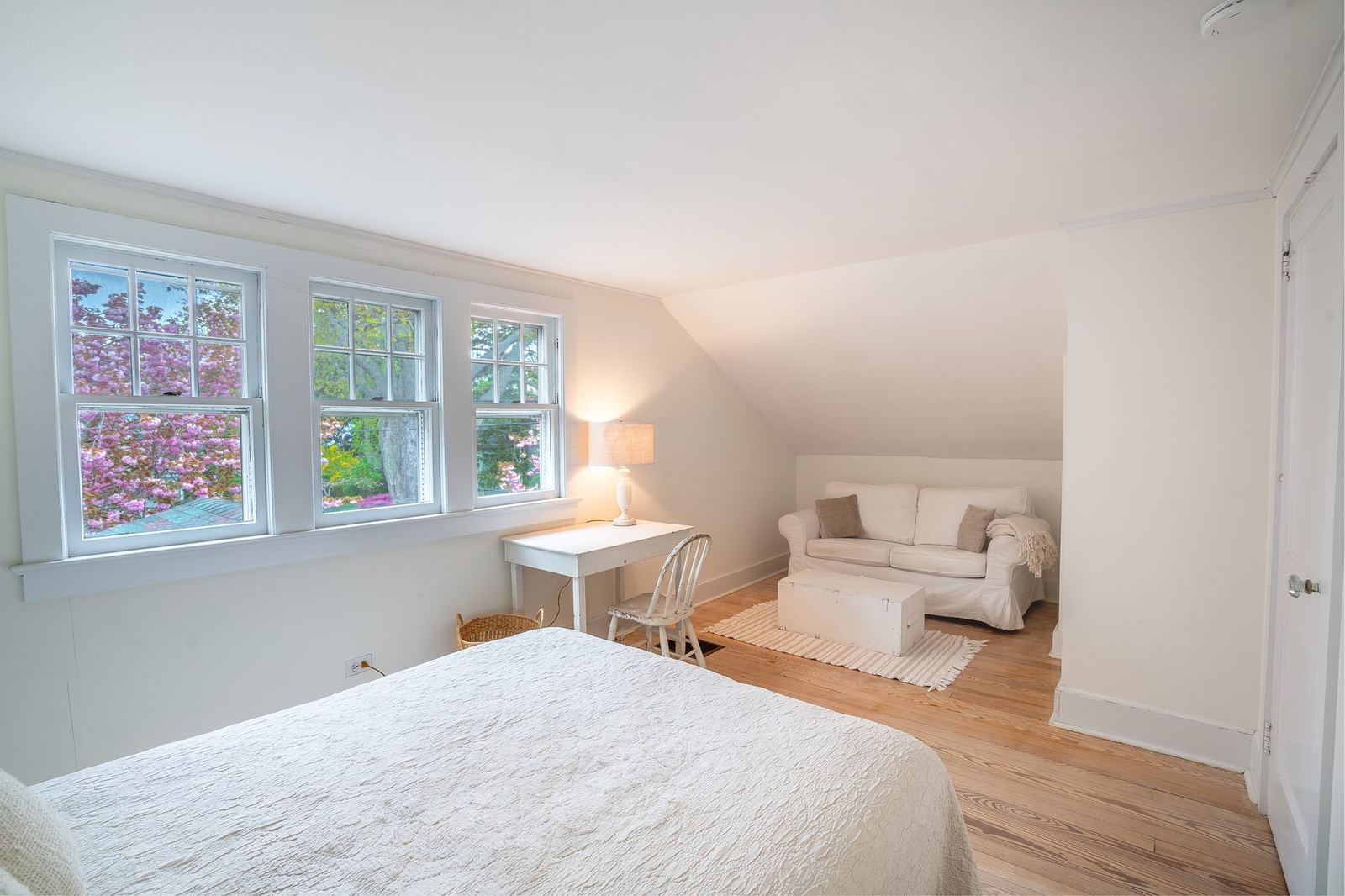 Primary bedroom under sloped roof with cherry blossoms outside